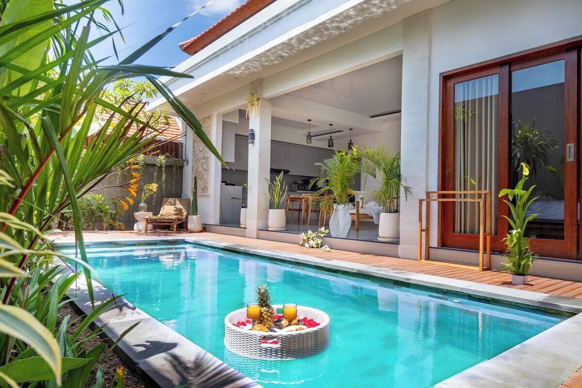 A modern outdoor pool area with a dining setup and potted plants.