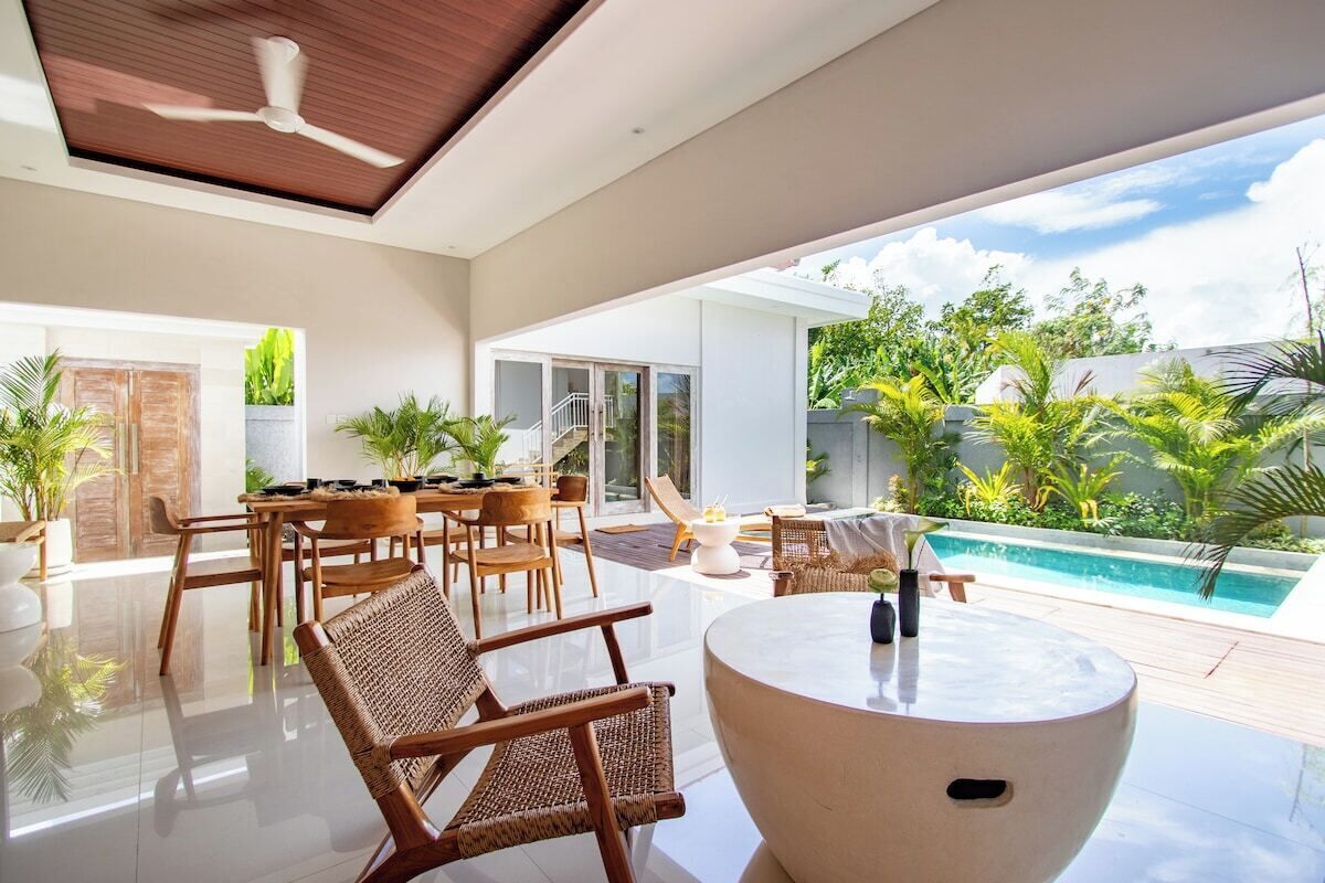 Interior moderno com área de jantar, mesa redonda e vista para uma piscina e vegetação.