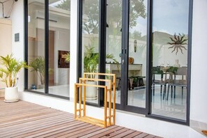 Un bâtiment moderne doté de grandes portes vitrées, d’une terrasse en bois et de plantes en pot.