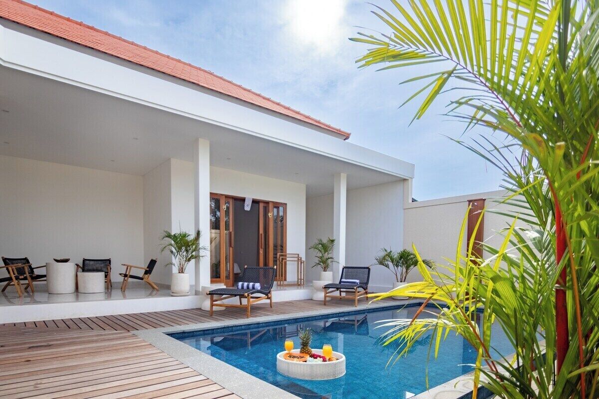 Un área de piscina exterior moderna con sillones de descanso y una mesa de comedor.