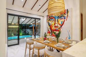 A dining area with a large painting, a pool view, and a modern interior design. - Blue Wave | 3BR Escape in Prime Ubud w Pool+Garden (Ubud)
