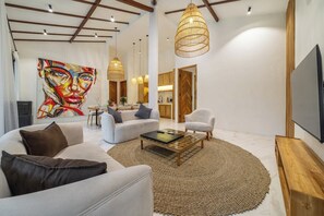 Een moderne woonkamer met een groot abstract schilderij, een bank, een salontafel en een televisie.