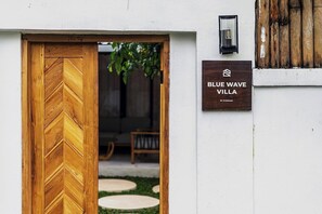 A wooden door with a chevron pattern, a sign reading 'BLUE WAVE VILLA,' and a small wall-mounted light fixture. - Blue Wave | 3BR Escape in Prime Ubud w Pool+Garden (Ubud)