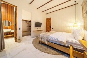 Un dormitorio con cama, televisor, armario de madera y baño con lavamanos y espejo.