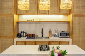 Una cocina con armarios de madera, una estufa a gas, un microondas y un lavamanos.