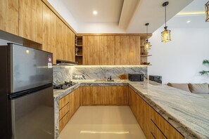 Eine moderne Küche mit Holzschränken, einer Marmorarbeitsplatte und einem integrierten Kühlschrank.