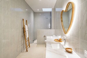 Een moderne badkamer met een grote spiegel, een douche en een wastafelmeubel met een wastafel en handdoekhouder.