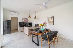 Eine moderne Küche mit einer zentralen Kochinsel, Essbereich mit Stühlen und Deckenventilator.