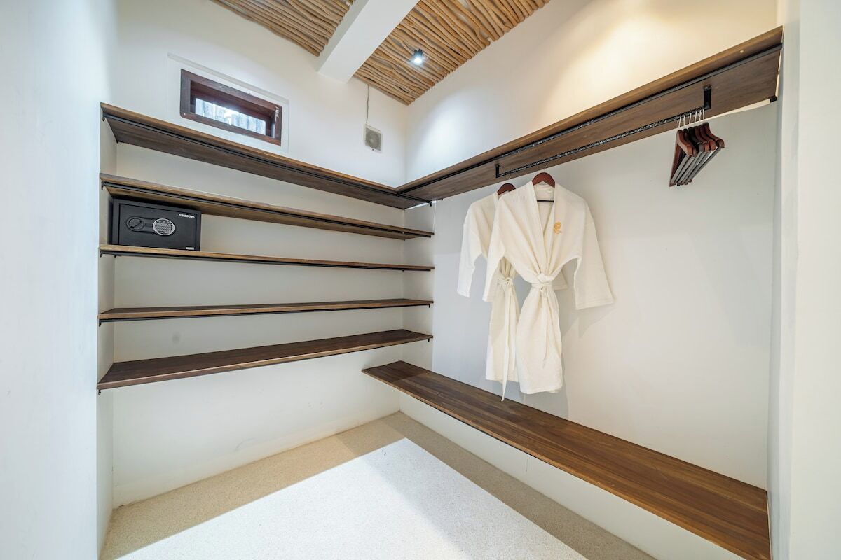 A room with wooden shelves, a white robe hanging, and a small radio.