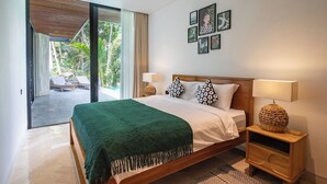 Ein modernes Schlafzimmer mit einem großen Bett, zwei Nachttischlampen und Blick auf einen tropischen Garten.