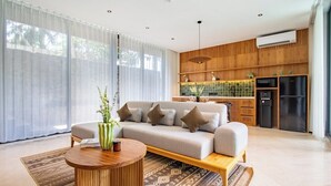 Ein modernes Wohnzimmer mit Sofa, Couchtisch und Küchenzeile mit Geräte.