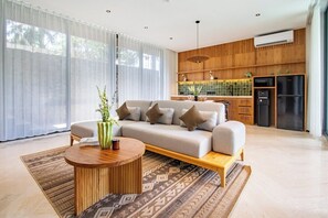Ein modernes Wohnzimmer mit Sofa, Couchtisch und Küchenzeile mit Geräte.