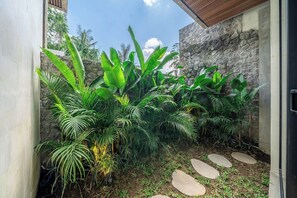 A garden with tropical plants and a stone wall. - Hidden Heaven 3BR Private Pool Villa Tropical Ubud (Gianyar Regency)