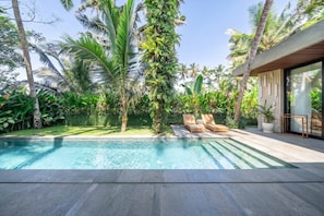 A modern pool area with a clear blue pool, surrounded by lush tropical vegetation and two lounge chairs. - Hidden Heaven 3BR Private Pool Villa Tropical Ubud (Gianyar Regency)
