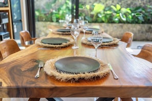 A wooden dining table set with plates, cutlery, and glasses, surrounded by chairs. - Hidden Heaven 3BR Private Pool Villa Tropical Ubud (Gianyar Regency)