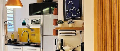 A modern kitchen with a black countertop, white cabinets, and a wooden wall panel.