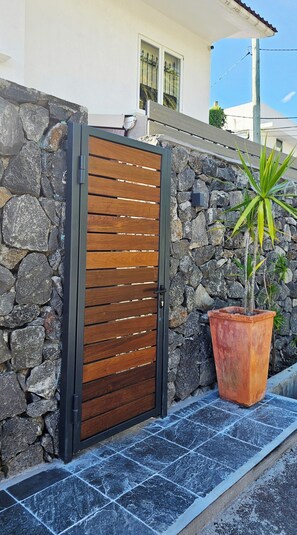 A stone wall with a wooden gate, a potted plant, and a tiled floor. - The loft - A charming hideaway heaven (Rivière Noire)