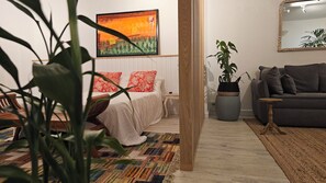 A room with a bed, a sofa, a large painting, and a potted plant. - The loft - A charming hideaway heaven (Rivière Noire)