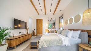 Ein modernes Schlafzimmer mit einem großen Bett, einem Holzkonsolentisch, einem Fernseher und einer großen Kübelpflanze.