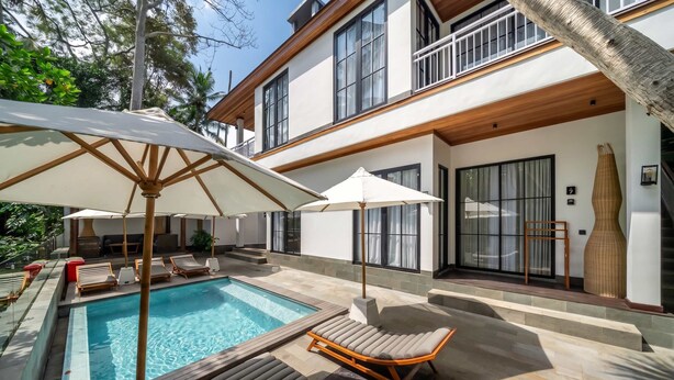 Ein modernes Haus mit Swimmingpool, Sitzgelegenheit im Freien und großen Fenstern.