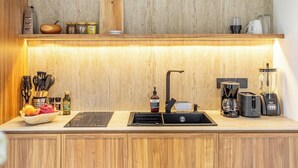 Eine moderne Küche mit Holzarbeitsplatte, integriertem Spülbecken und verschiedenen Geräten, darunter eine Kaffeemaschine und ein Toaster.
