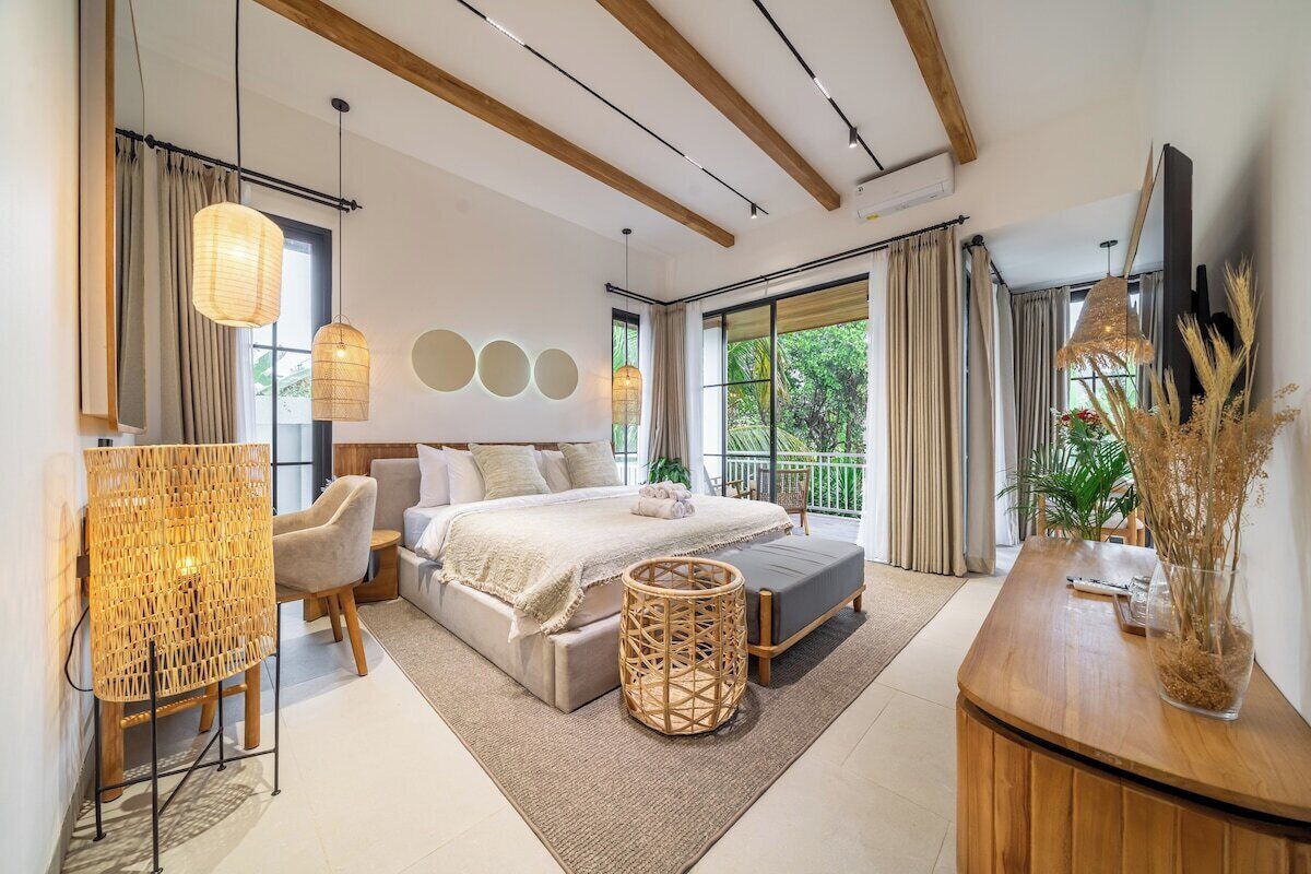 Un dormitorio moderno con una cama grande, mesitas de noche, una zona de estar y un balcón con vistas.