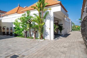 A building with a tiled roof, white walls, and a paved entrance area with potted plants. - Brand new private villa, large pool, beach access (Kabupaten Badung)
