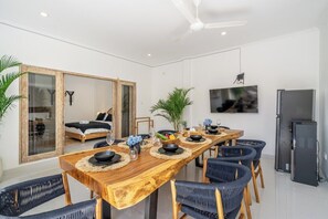 A modern dining area with a wooden table set for six, surrounded by black chairs. - Brand new private villa, large pool, beach access (Kabupaten Badung)