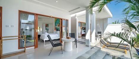 A modern interior with a white sofa, a dining table, and a staircase leading to an outdoor area.