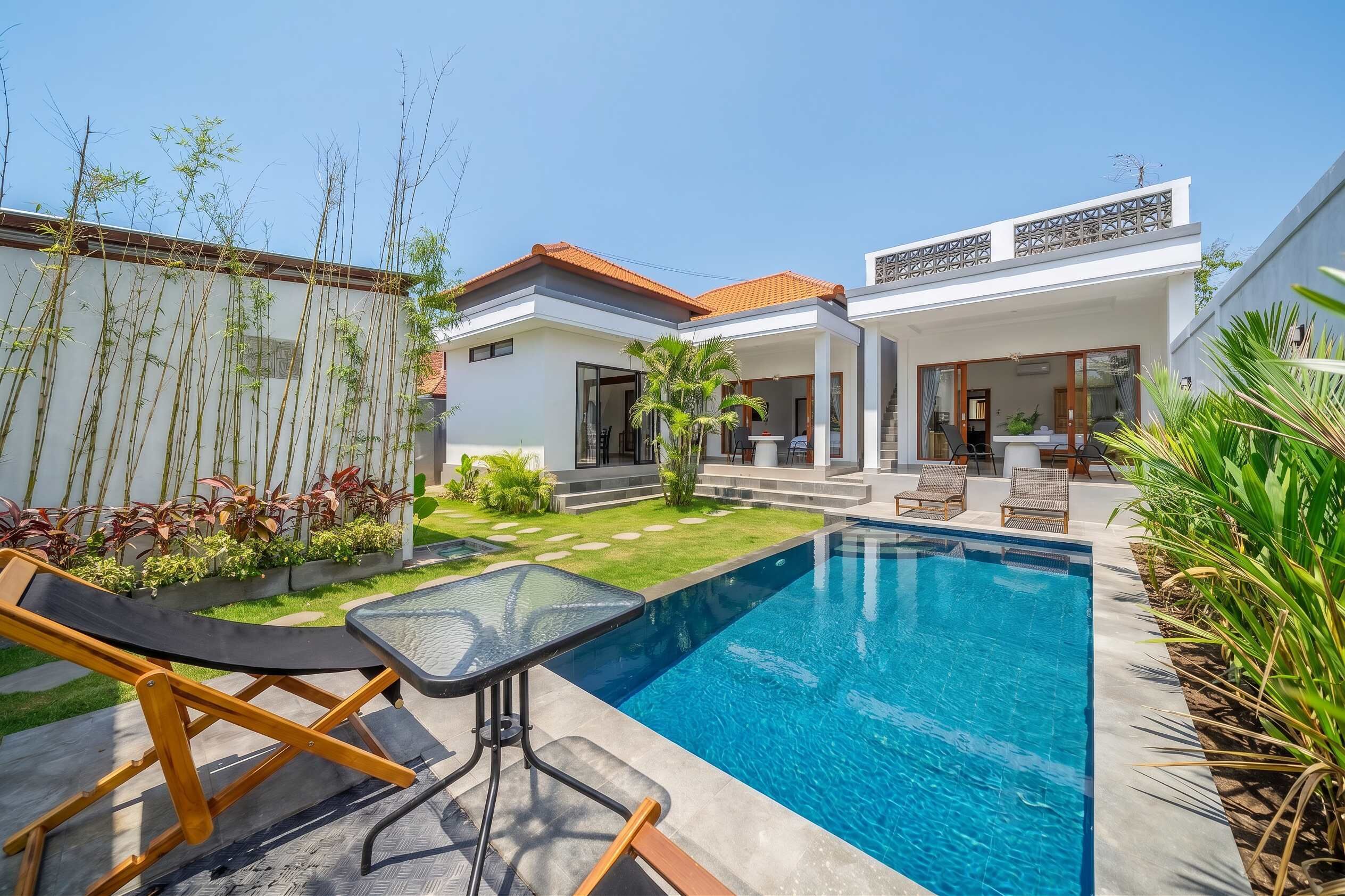 Une maison moderne dotée d’une piscine, de mobilier d’extérieur et d’un jardin bien entretenu.