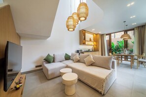 Ein modernes Wohnzimmer mit einer Eckcouch, einem runden Couchtisch und einem Flachbildfernseher.