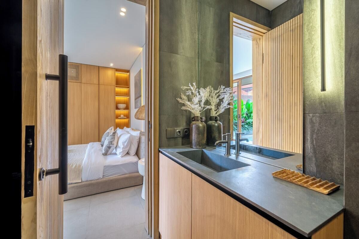 Un baño moderno con un espejo grande, un lavamanos y una zona de ducha.