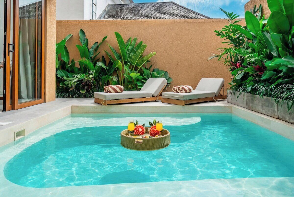 A swimming pool with lounge chairs and a floating basket with fruits.