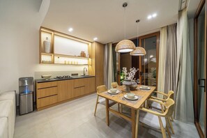 Eine moderne Küche mit Holzschränken, einem Einbauofen und einem Essbereich mit Holztisch und -stühlen.