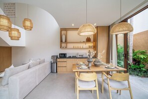Eine moderne Küche mit Essbereich, ausgestattet mit einem Holztisch, Stühlen und Pendelleuchten.