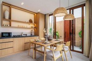 Eine moderne Küche mit Holzschränken, einem Esstisch und einem großen Fenster.