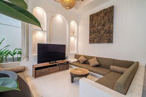 Un saló modern amb televisió de pantalla plana, un sofà, una taula de centre i una obra decorativa a la paret.