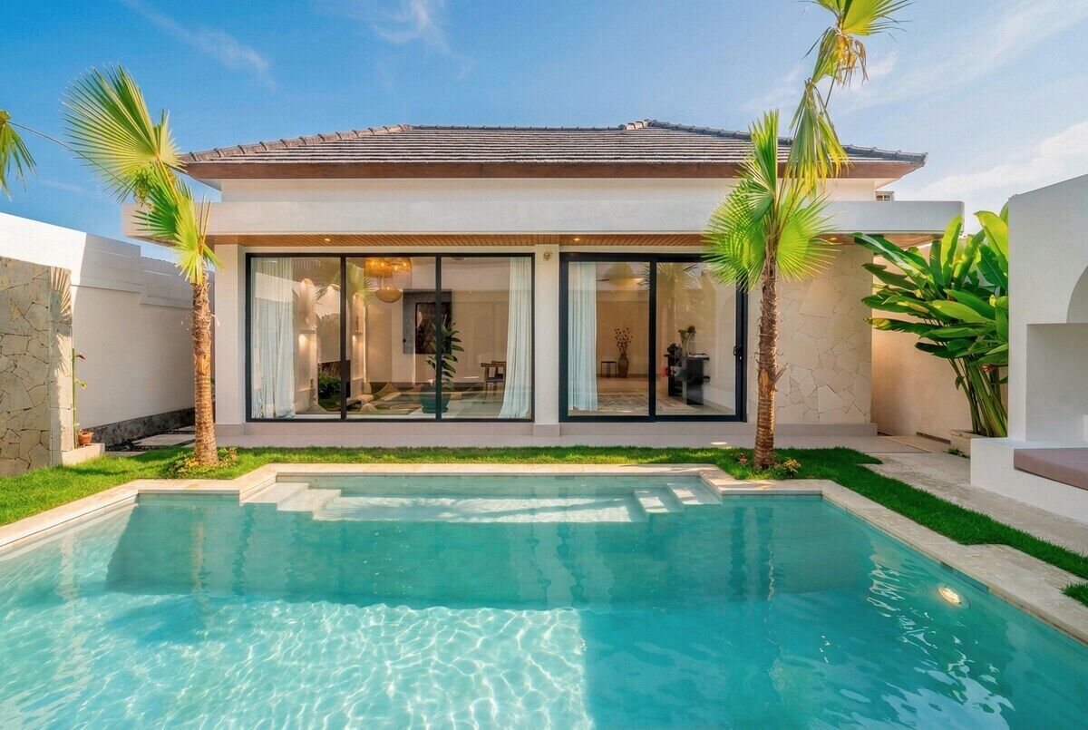 Ein modernes Haus mit Swimmingpool, großen Fenstern und Palmen.