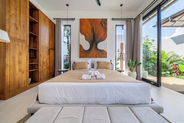 Een moderne slaapkamer met een groot bed, een houten garderobe en uitzicht op groen.