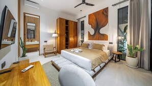 Una moderna camera d'albergo con un letto grande, una scrivania, una sedia, una ventola a soffitto e un'ampia finestra con tende.
