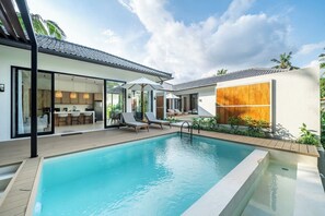 Een modern zwembad met helder water, ligbedden en een eethoek met terrasmeubilair.
