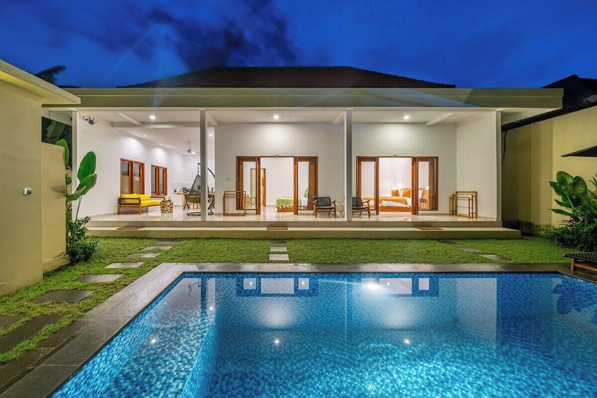 A modern house with a swimming pool, a covered patio, and a well-maintained lawn.