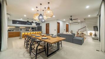 A modern kitchen with a dining area, a grey sofa, and a staircase.