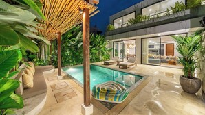 Una casa moderna con piscina, area relax esterna e vegetazione lussureggiante.