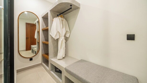 Un bagno con una panca, un appendiabiti e uno specchio.