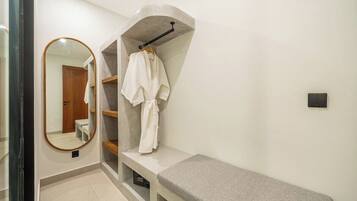 A bathroom with a bench, a robe rack, and a mirror.