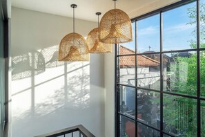 Un escalier doté d’une rampe en verre, menant à un balcon avec de grandes fenêtres.