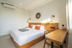 Une chambre d’hôtel équipée d’un lit, d’une table de chevet, d’une lampe et d’un climatiseur fixé au mur.