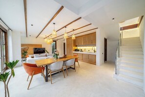 Eine moderne Küche mit Holzschränken, Pendelleuchten und einem Essbereich mit Holztisch und Stühlen.