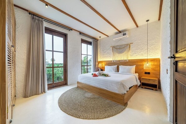 Un dormitorio con una cama grande, un tapete redondo tejido, un cabecero de madera y vistas a zonas verdes.